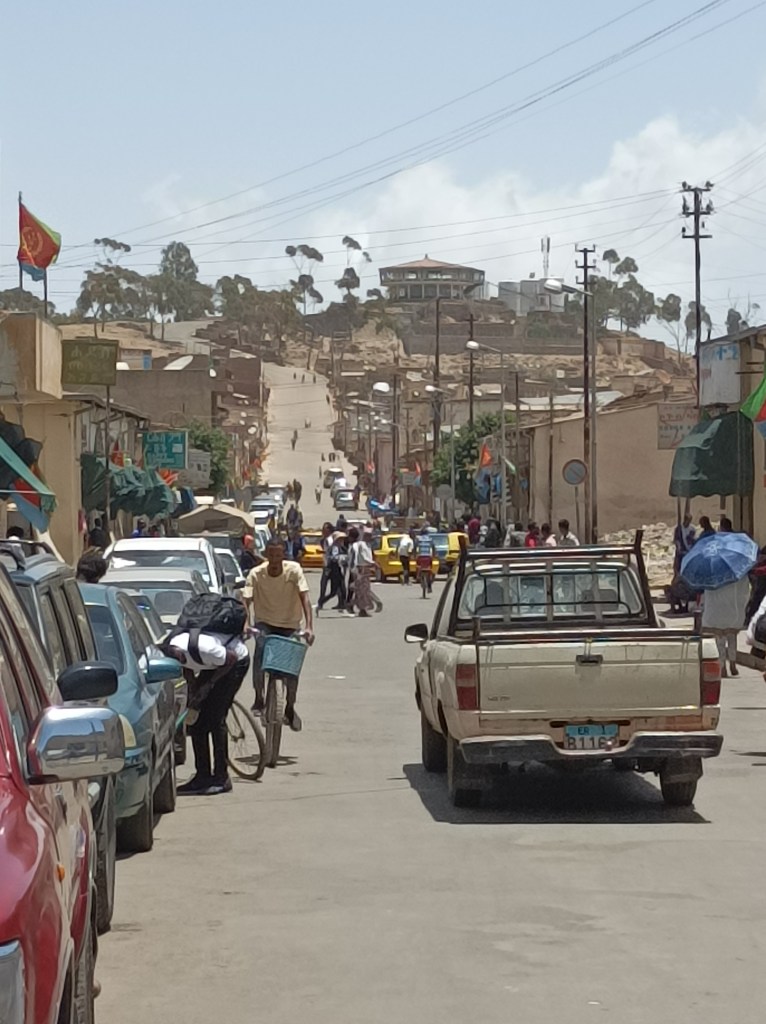 Pogled iz grada prema vidikovcu. Klinci igraju nogomet na cesti kojom ćemo se popeti do gore.